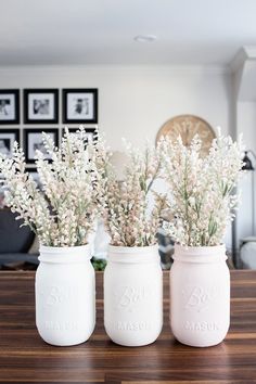 three mason jars with flowers in them sitting on a table