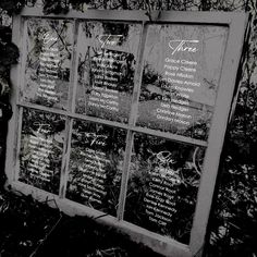 an old window with some writing on it and plants in the backgroung