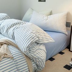 a bed with blue and white striped comforter on top of it next to a night stand