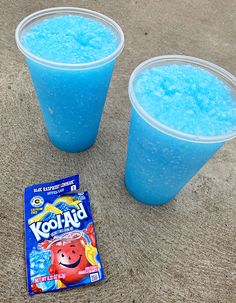 two plastic cups filled with blue liquid next to a bag of kooly cereal