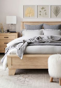 a bedroom with a bed, dressers and two pictures on the wall above it