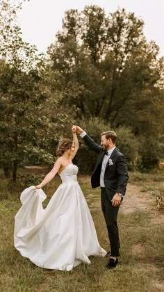 a bride and groom dancing in the grass