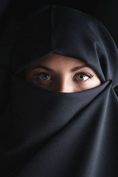 a woman wearing a black hijab and looking at the camera with her eyes wide open