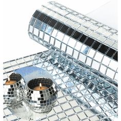 two disco ball candles sitting on top of a mirrored table next to a roll of tape