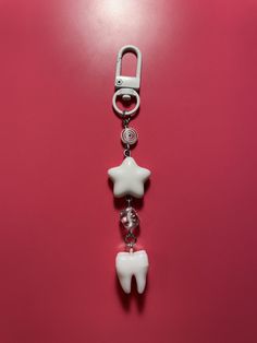 a tooth shaped key chain on a pink background