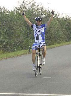 a man riding a bike with his arms up in the air on a paved road