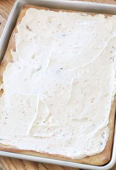 a pan filled with white frosting on top of a wooden table