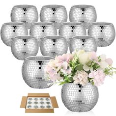 a vase filled with lots of flowers next to a box full of silver disco balls