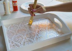 a person holding a paintbrush in front of a white tray