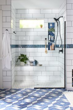 a bathroom with blue and white tiles on the floor, shower head, and bathtub