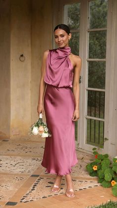 a woman in a long pink dress holding a bouquet and standing on a tile floor