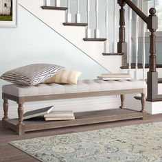 a white bench sitting under a staircase next to a stair case and rug on top of a hard wood floor