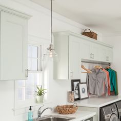 a kitchen with white cabinets and stainless steel dishwasher next to a washer and dryer