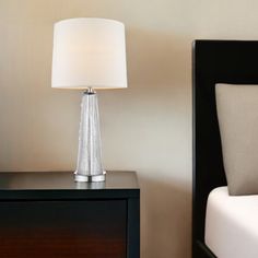 a lamp on a nightstand next to a bed