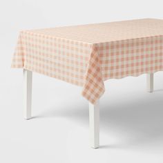 an orange and white checkered table cloth on top of a white wooden bench with legs