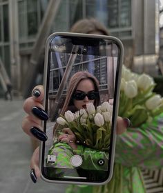 a woman taking a selfie with flowers in front of her on her cell phone