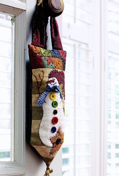 a snowman decoration hanging from the side of a window sill with buttons on it