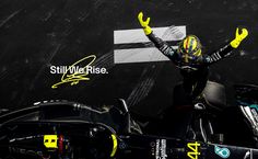 a man standing on top of a race car in front of a black background with yellow writing