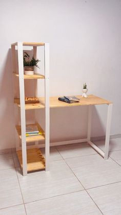 a white desk with some books on it and a plant in the corner next to it