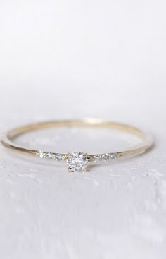 a yellow gold ring with a diamond set in the middle, sitting on a white surface