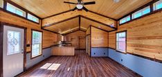 the inside of a tiny house with wood flooring and windows on each side of the room