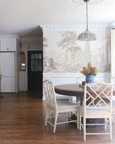 a dining room table with four chairs and a wallpapered background on the wall