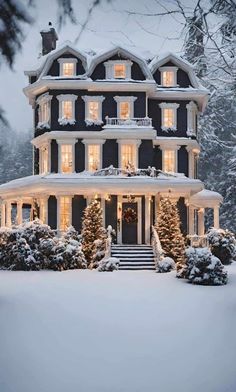 a large black house covered in snow with christmas lights on the windows and steps leading up to it