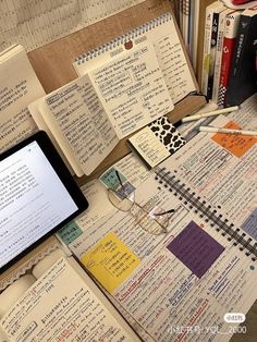 several notebooks are spread out on a table with an electronic device and other items