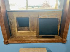 a wooden shelf with two empty blackboards on it in front of a blue wall