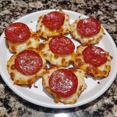 small slices of pepperoni pizza on a white plate sitting on a granite counter top