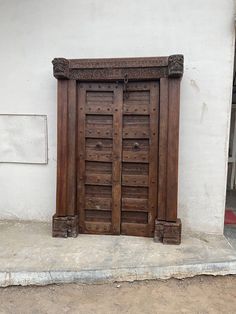 an old wooden door on the side of a white building with no people around it