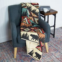 a chair with a blanket on it in front of a table and rug that has a bear design