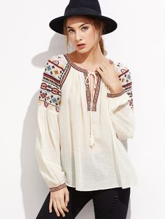 a woman wearing a black hat and white blouse posing for the camera with her hand on her hip