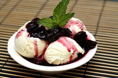 an ice cream sundae with blueberries and mint on top is served in a white bowl