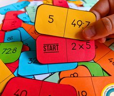 a hand is pointing at some colorful numbers on a table with matching cards in front of it