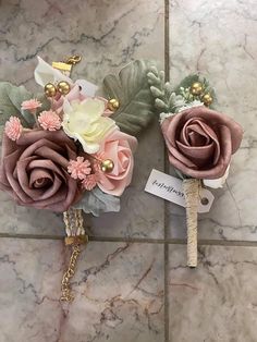 two boutonnieres with flowers on them sitting on a tile floor next to each other