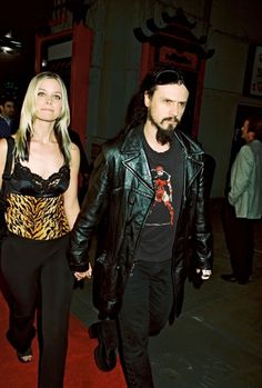 a man and woman walking down a red carpeted street holding hands with each other