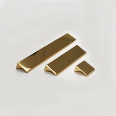 two pieces of brass metal on a white surface