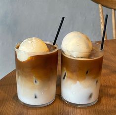 two glasses filled with ice cream on top of a wooden table