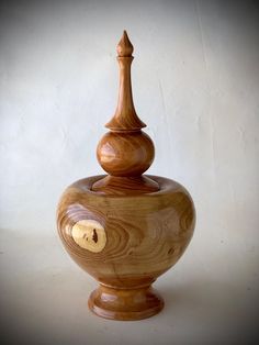 a wooden vase with a chess piece on it's top, sitting in front of a white wall