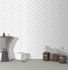 a coffee maker sitting on top of a counter next to two jars and a cup