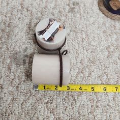 a roll of tape sitting on top of a floor next to a measuring tape holder