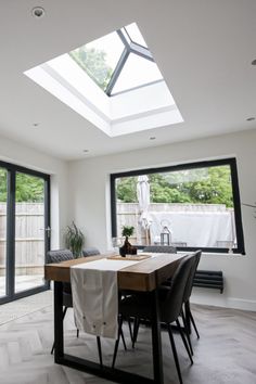 a dining room table with chairs and a skylight in the middle of an open floor plan