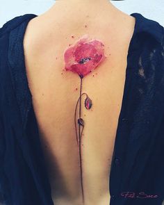 the back of a woman's shoulder with a flower tattoo on her left side