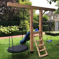 a wooden swing set with a blue slide and swings in the grass next to it