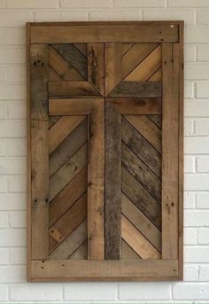 a cross made out of wooden planks mounted on a wall above a green shelf