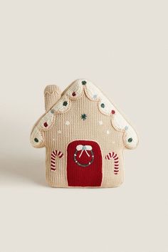 a small knitted house ornament on a white background with red and green accents