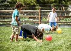 three children are playing with balls in the grass