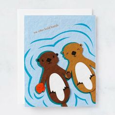 two brown bears standing next to each other on top of a blue card that says we are otters holding hands