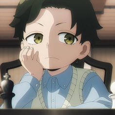 an anime character sitting at a desk with his hand on his face and looking off to the side